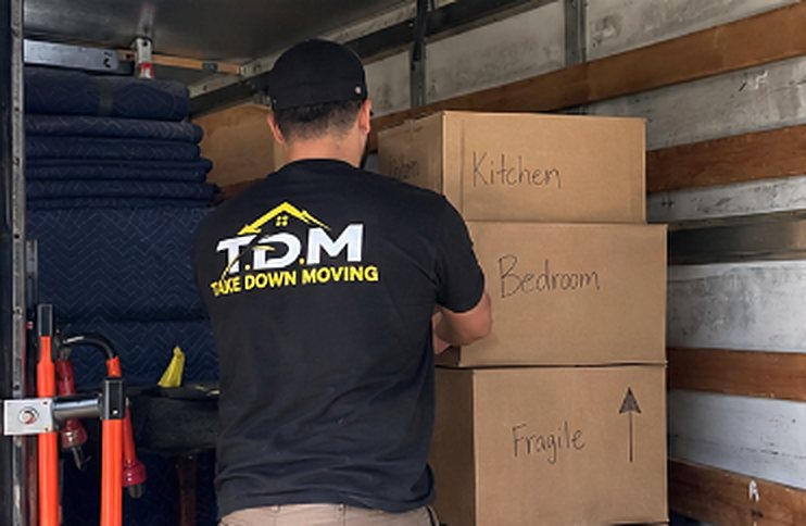 T.D.M mover loading labeled boxes into a moving truck